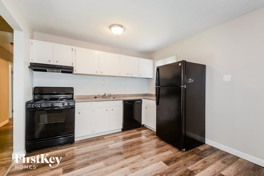 a kitchen with white cabinets and black appliances and a refrigerator
