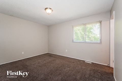 the living room of a small white house with carpet and a window