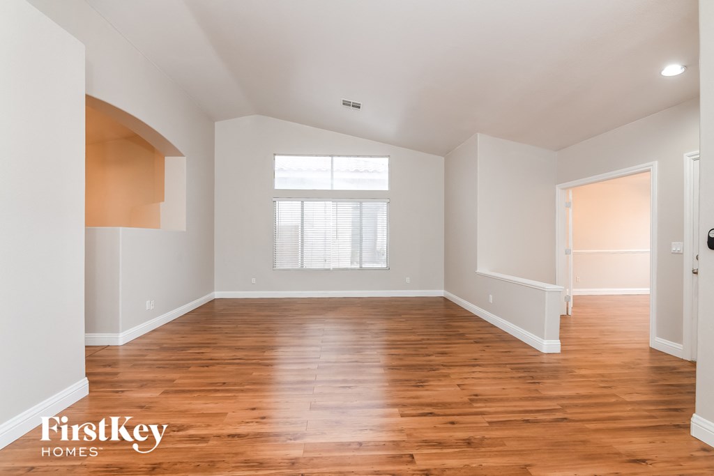 A spacious room with wooden floors and white walls.