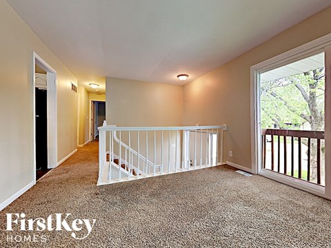 the upstairs loft has a large window and a white staircase