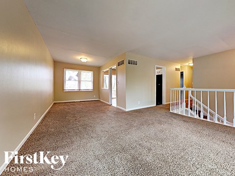 an empty living room with carpeted floors and a staircase
