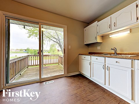a kitchen with white cabinets and a sliding glass door to a deck