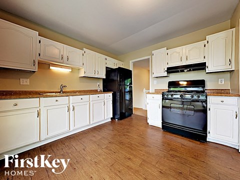 a large kitchen with white cabinets and black appliances