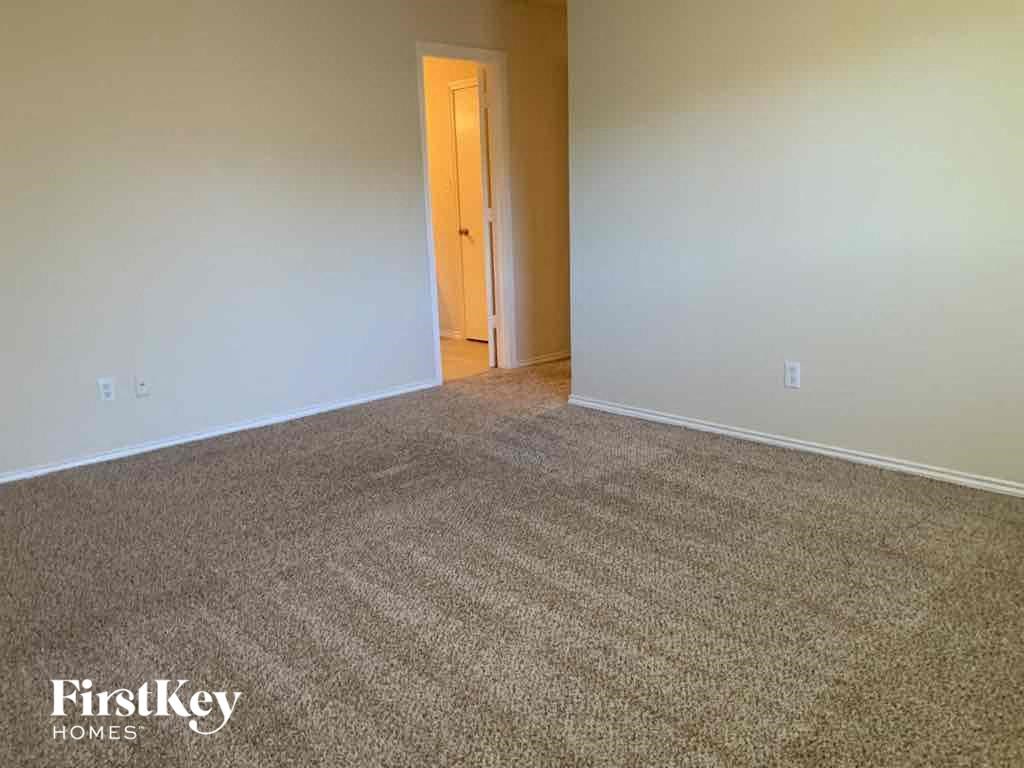 an empty living room with carpet and a door to a hallway