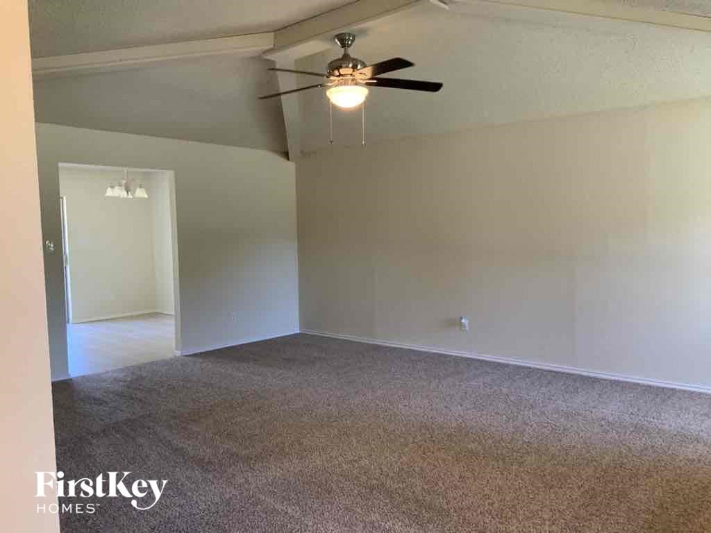 an empty living room with a ceiling fan