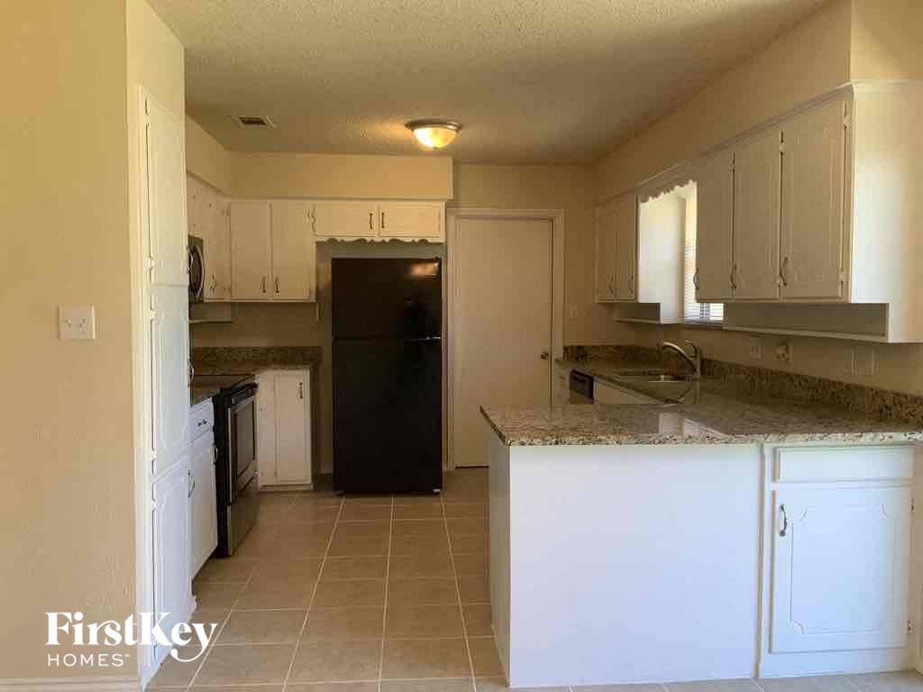 a kitchen with white cabinets and a black refrigerator