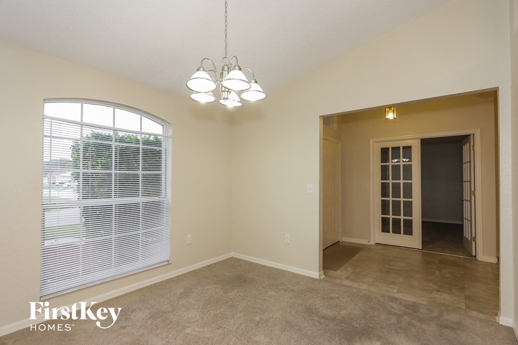 an empty living room with a large window and a door to a hallway