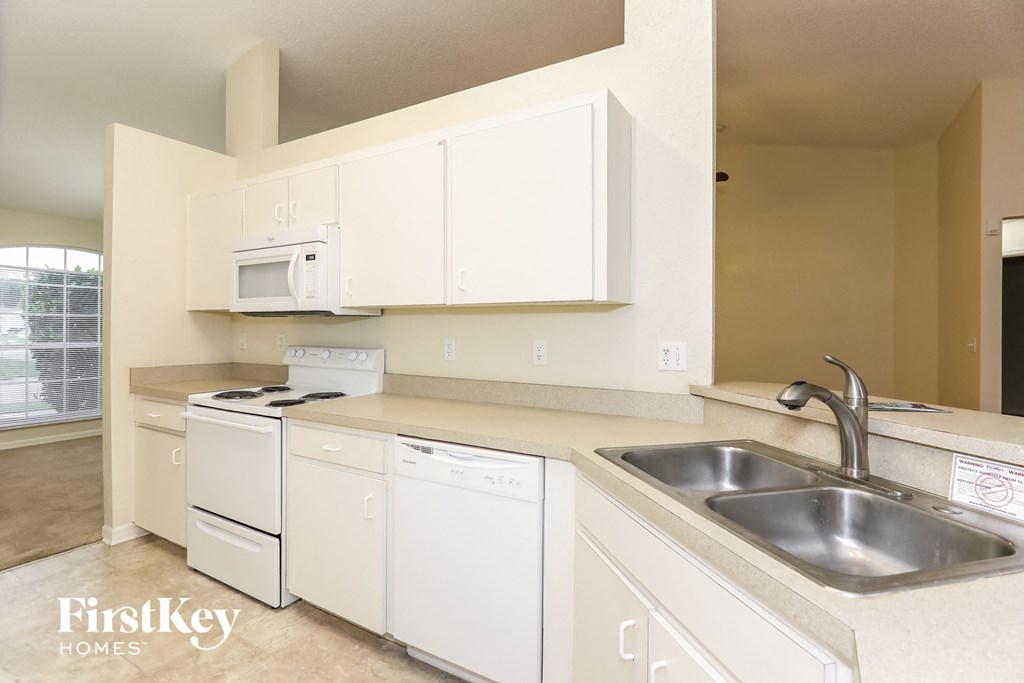 a kitchen with white cabinets and appliances and a sink