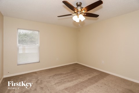 a living room with a ceiling fan and a carpet