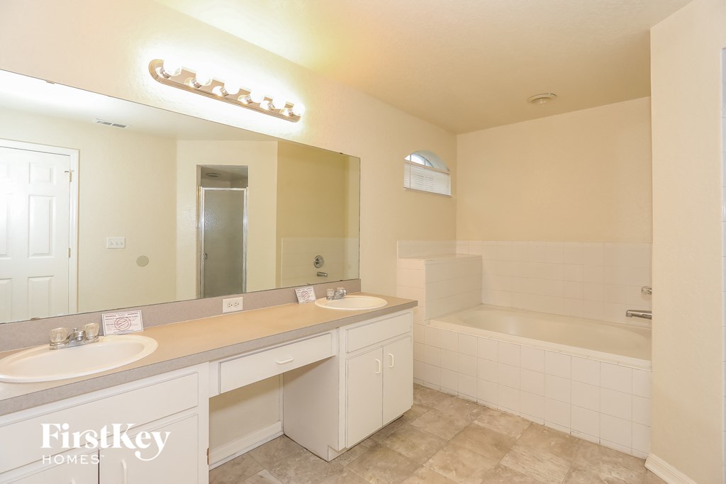 a bathroom with two sinks and a tub and a mirror