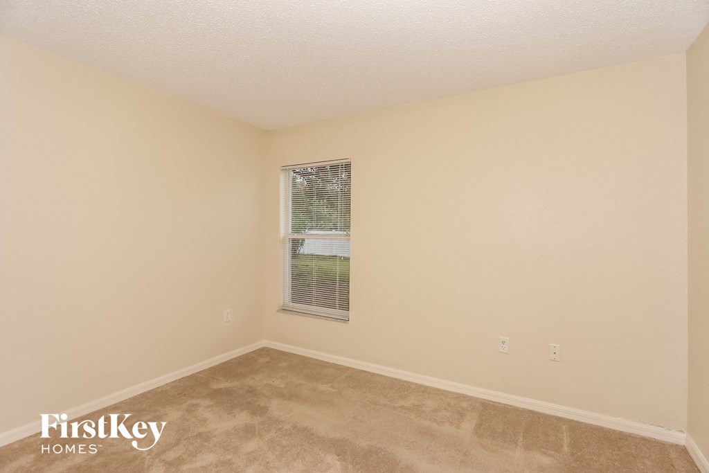 a bedroom with a window and a carpeted floor