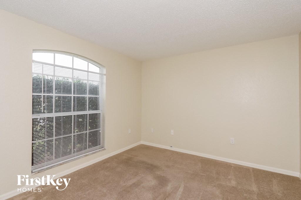 an empty living room with a large window and carpet