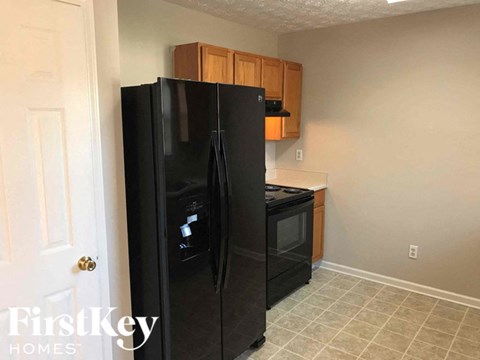 A black fridge and oven in a kitchen with wooden cabinets.
