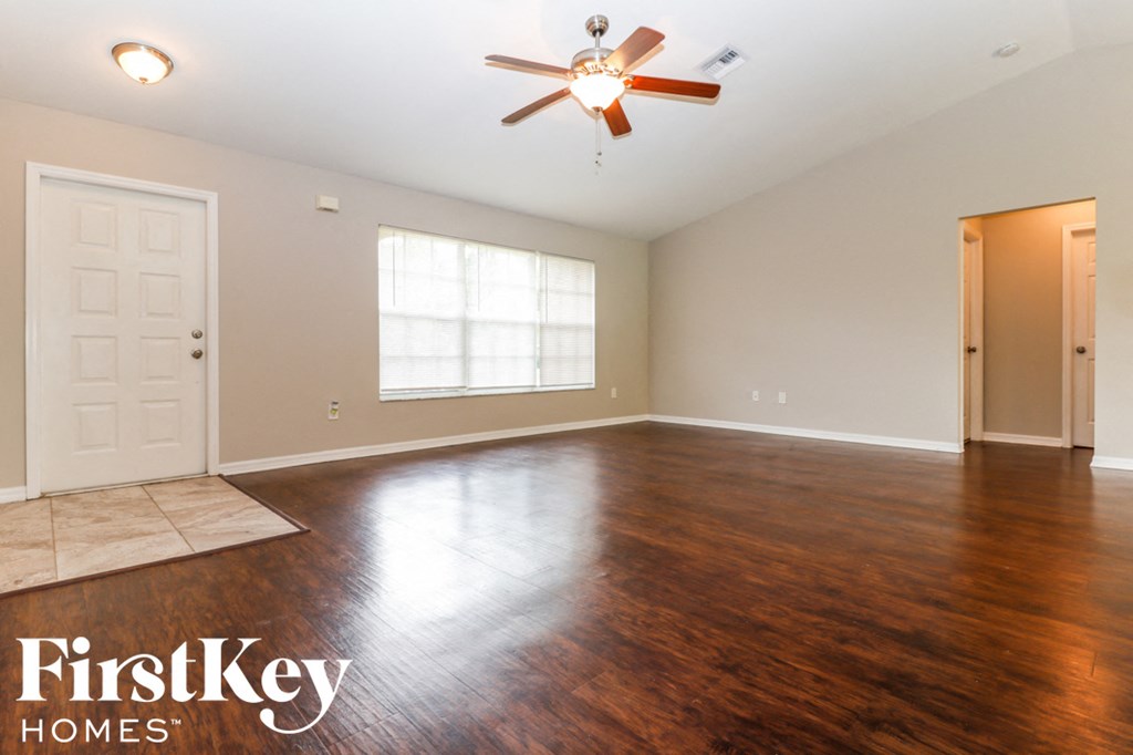 A spacious room with a ceiling fan and wooden flooring.