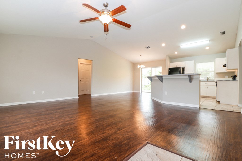 A spacious room with a ceiling fan and wooden flooring.