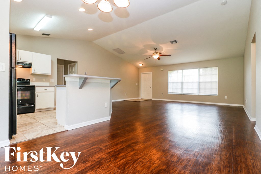A spacious kitchen and living room with wooden floors and a ceiling fan.