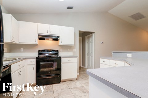 A kitchen with a black stove top oven and white cabinets.