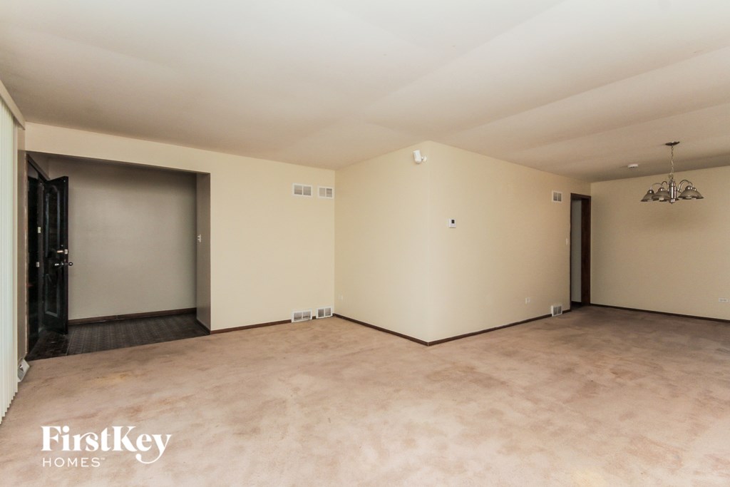 A spacious empty room with a FirstKey HOMES logo on the bottom left.