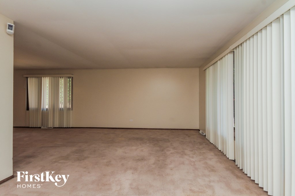 A room with a carpeted floor and a window with curtains.