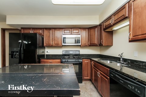 A kitchen with a black counter top and wooden cabinets.
