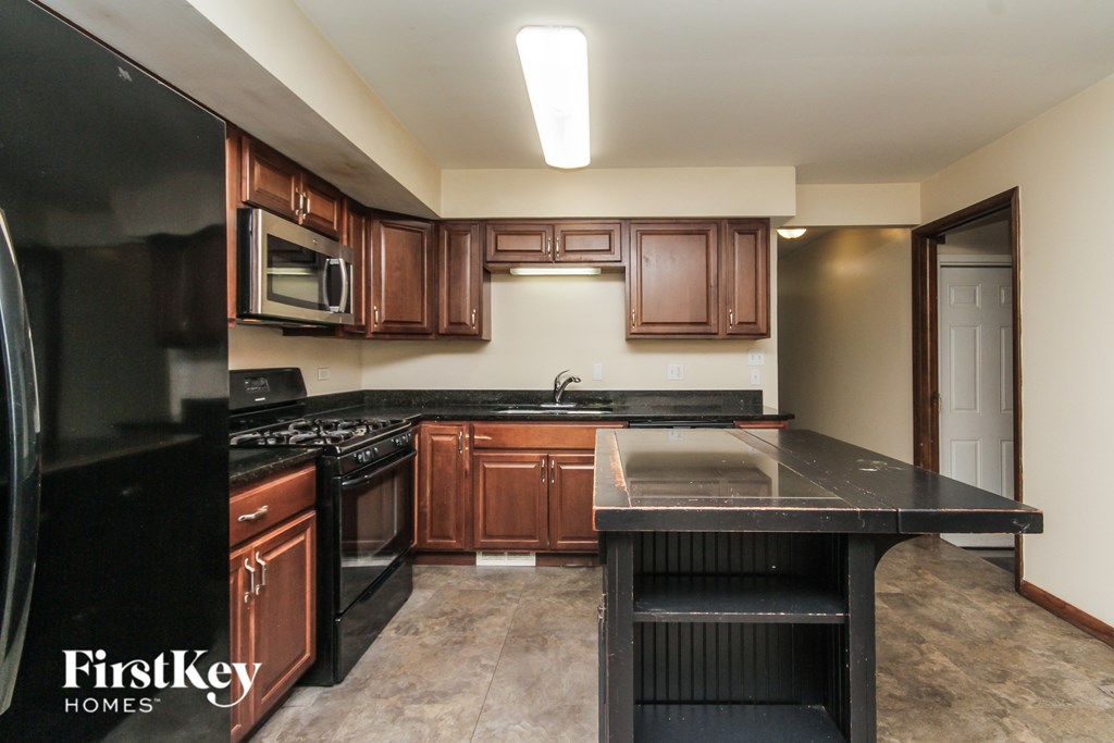 A kitchen with brown cabinets and black appliances.
