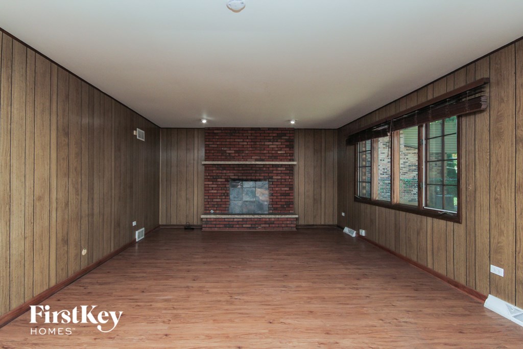 A room with wooden walls and a brick fireplace.