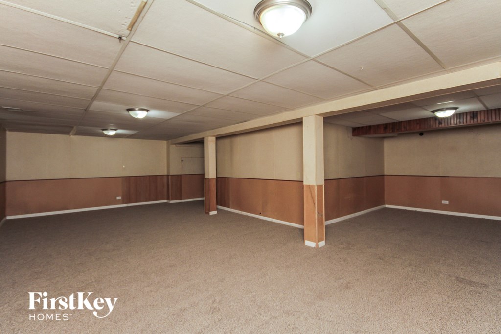 A spacious room with a carpeted floor and a FirstKey HOMES logo on the bottom left.