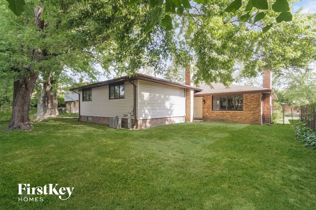 A house with a lawn and trees in the background is for sale.