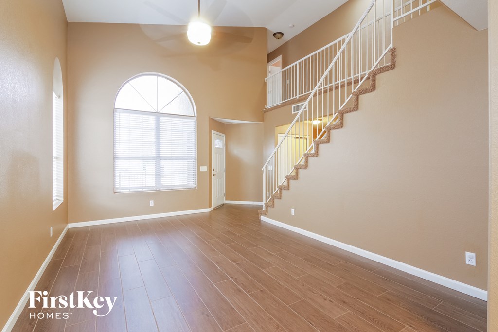 the foyer and living room of an empty house with a staircase and a window