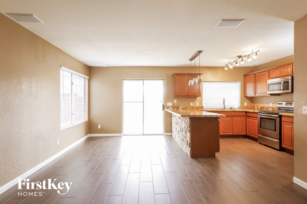 an empty kitchen with wood flooring and a granite counter top