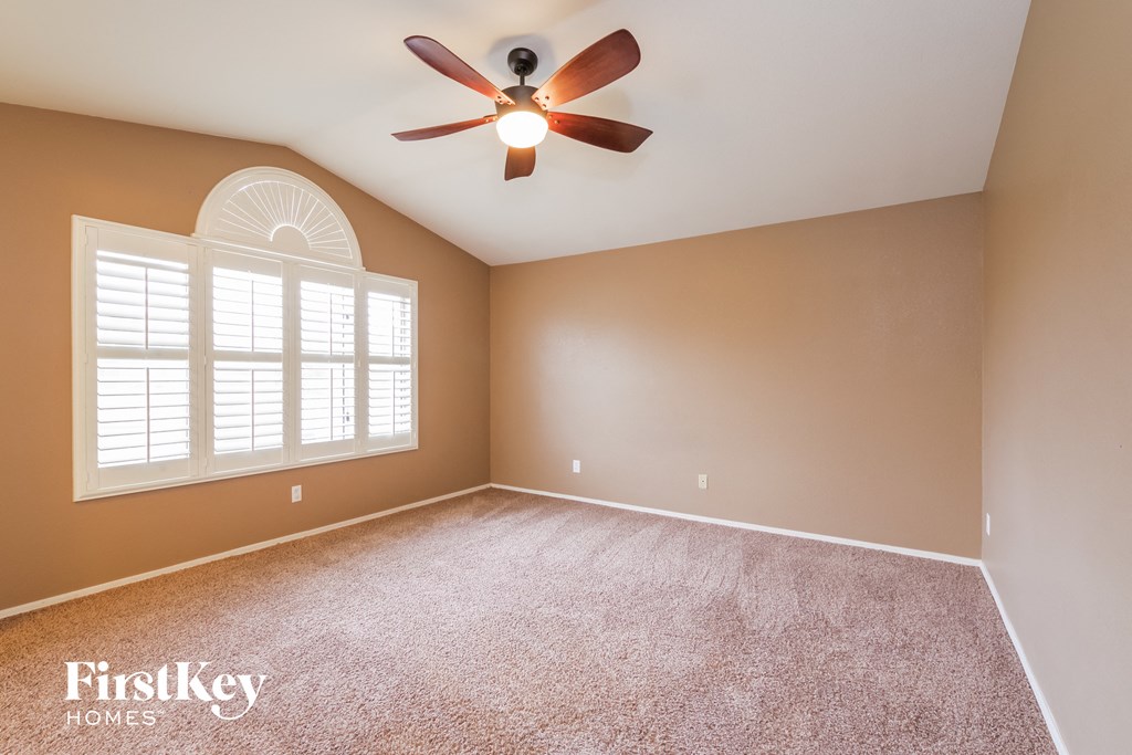 an empty living room with a ceiling fan and a window