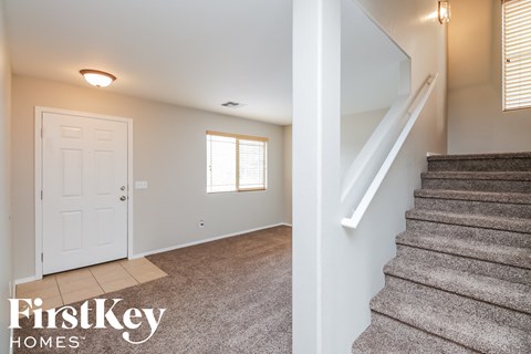 the entryway of a house with stairs and a white door