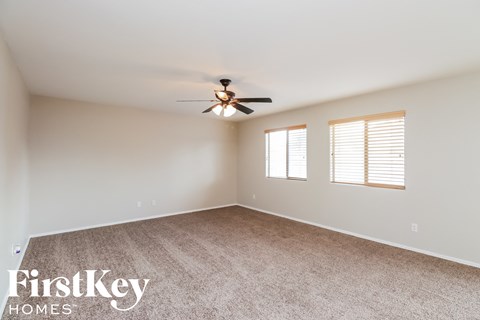 an empty living room with a ceiling fan and window