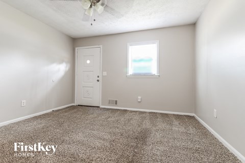 a spacious living room with carpet and a ceiling fan