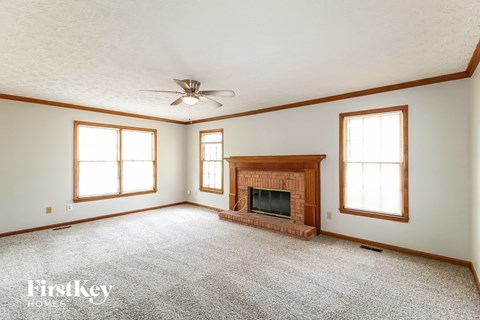 A spacious living room with a fireplace and a ceiling fan.
