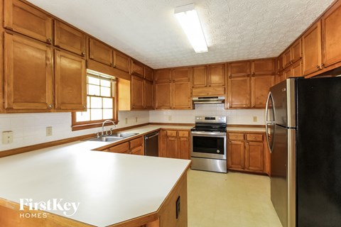 A kitchen with wooden cabinets and a black refrigerator.