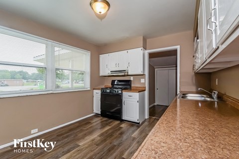 A kitchen with a black stove top oven and white cabinets.