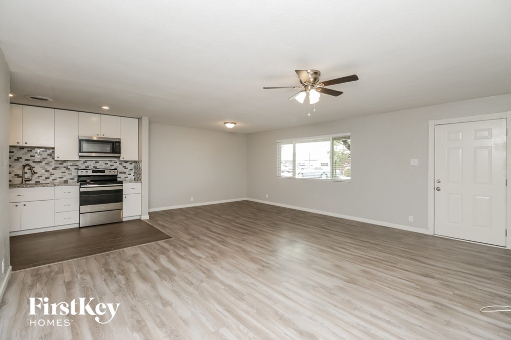 the living room and kitchen of an empty house with a ceiling fan