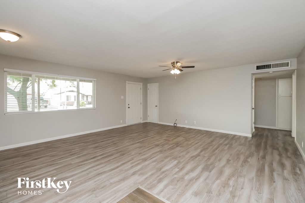 the living room of an empty house with a ceiling fan