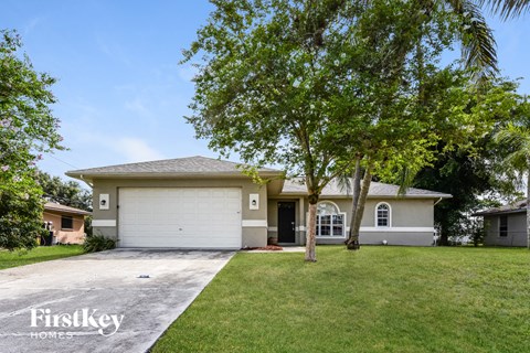 a white house with a driveway and a tree
