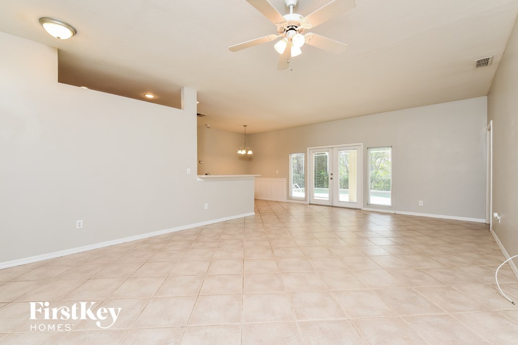 an empty living room with a ceiling fan and a window
