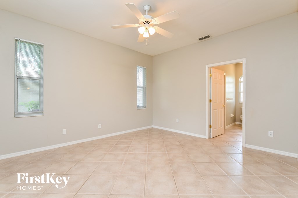 a spacious living room with a ceiling fan and tile flooring
