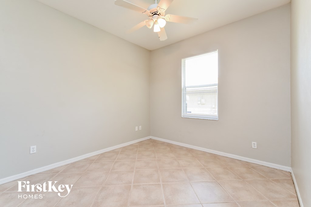 an empty room with a ceiling fan and a window