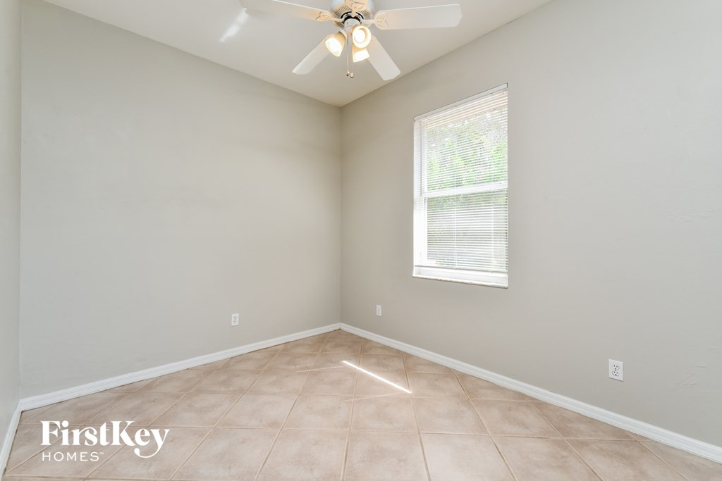 an empty room with a ceiling fan and a window