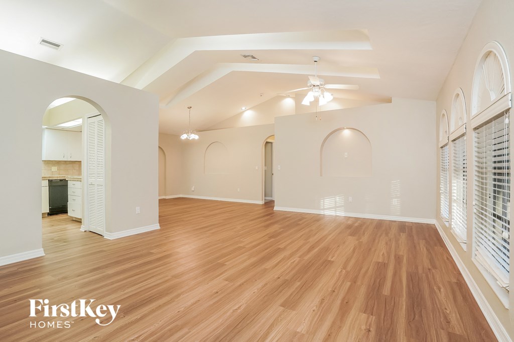 A spacious room with wooden flooring and arched doorways.
