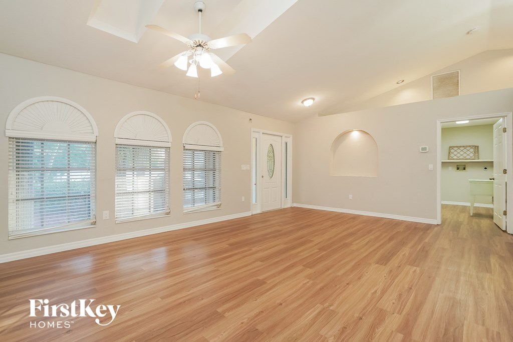 A spacious room with wooden floors and arched windows.