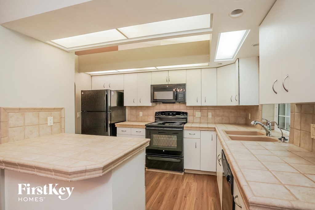 A kitchen with a black refrigerator, stove, and oven.