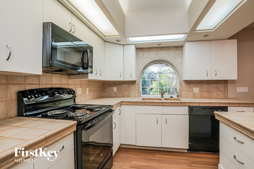 A kitchen with a black stove top oven and white cabinets.