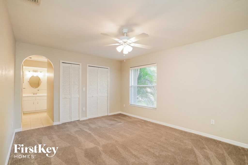 A room with a carpeted floor and a ceiling fan.