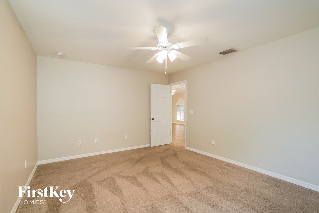 A spacious room with a carpeted floor and a ceiling fan.